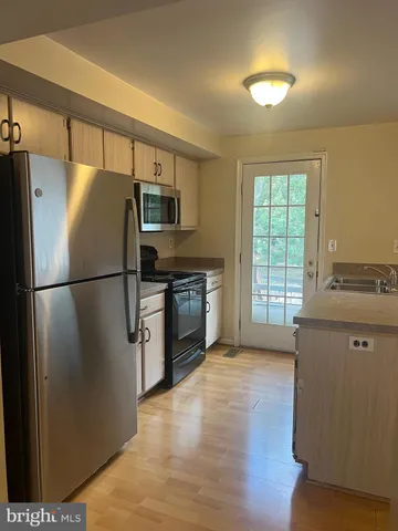 a kitchen with granite countertop stainless steel appliances a refrigerator cabinets and wooden floor