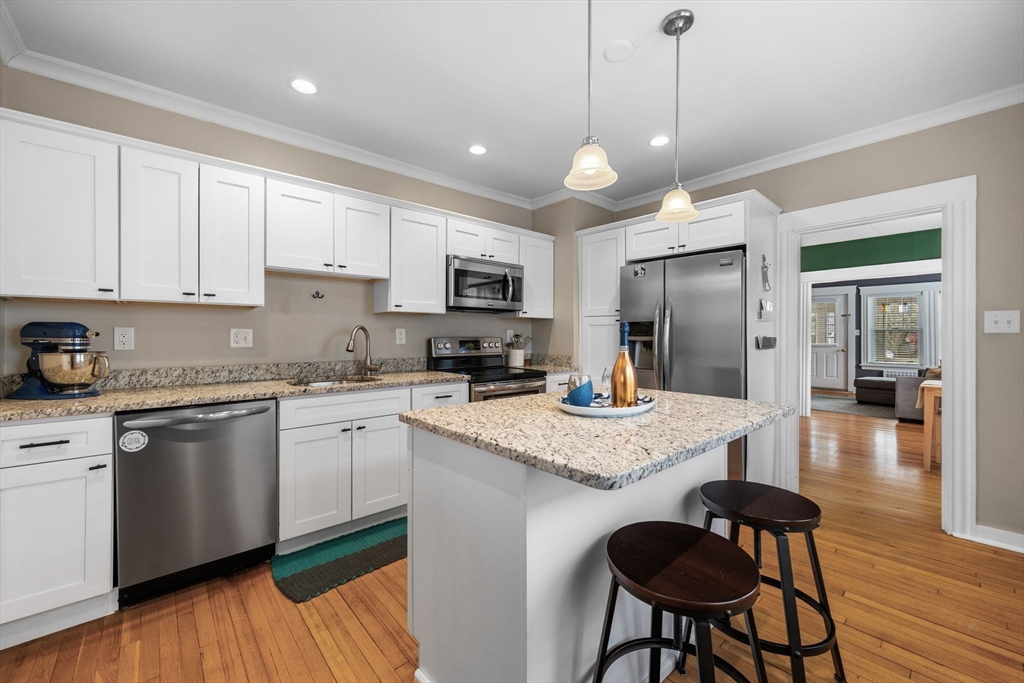 34 Moffatt Road, Unit 34 Salem, MA 01970 - Photo 6 of 23 a kitchen with stainless steel appliances granite countertop a stove a sink a refrigerator a microwave oven a dining table and chairs with wooden floor