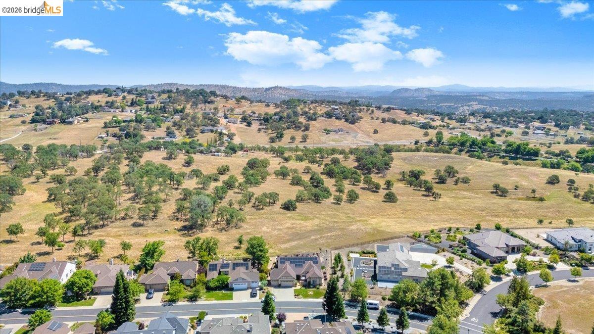 158 Rock Ridge Lane Copperopolis, CA 95228 - Photo 61 of 72 Expansive aerial capturing residential properties with traditional architecture, paved streets, and a backdrop of rolling, tree-dotted hills