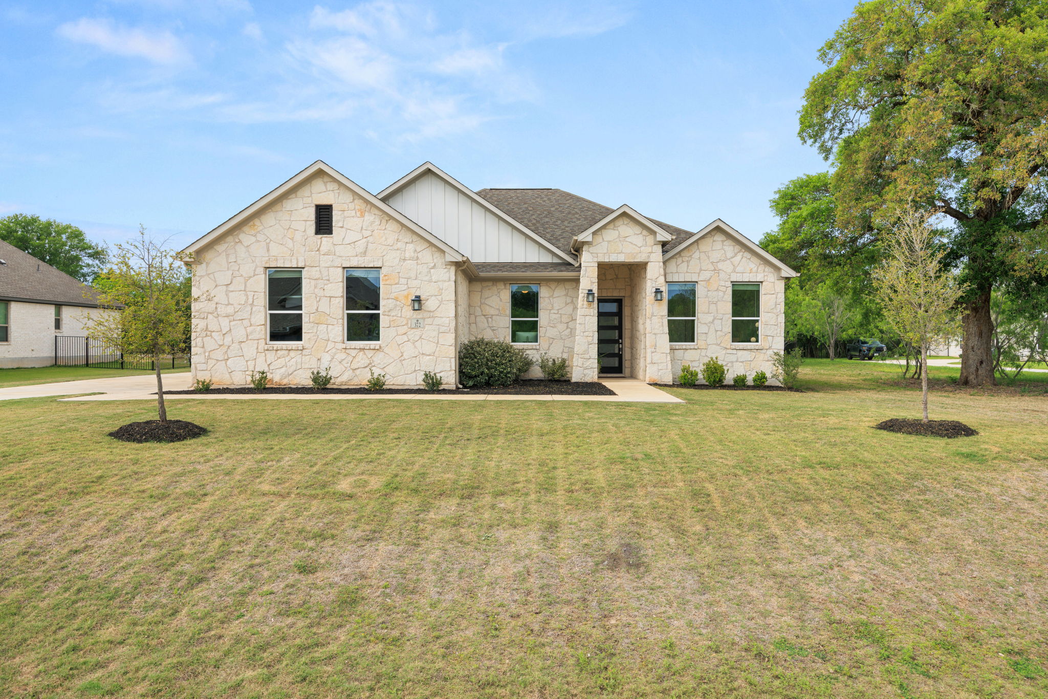372 Raptor Beak Way Cedar Creek, TX 78612 - Photo 1 of 1 View of front of house with board and batten siding, stone siding, a front yard, and roof with shingles, on over an acre of land