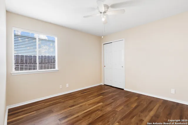 a view of empty room with wooden floor and fan