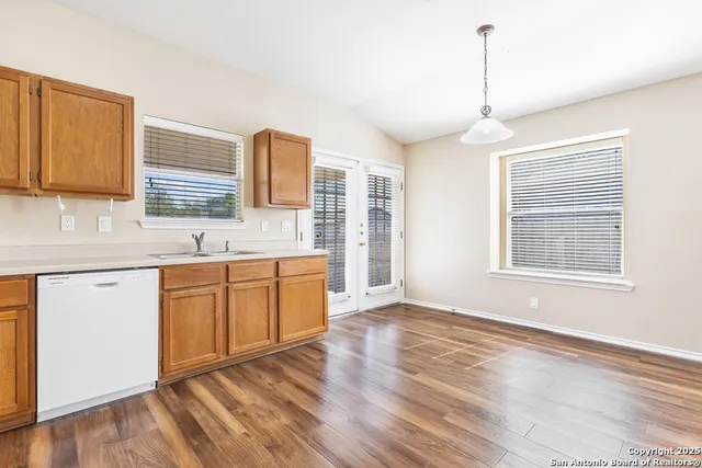 a kitchen with stainless steel appliances granite countertop a sink cabinets wooden floor and a window