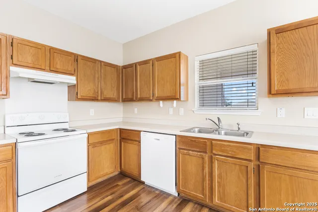 a kitchen with a sink cabinets wooden floor and a window