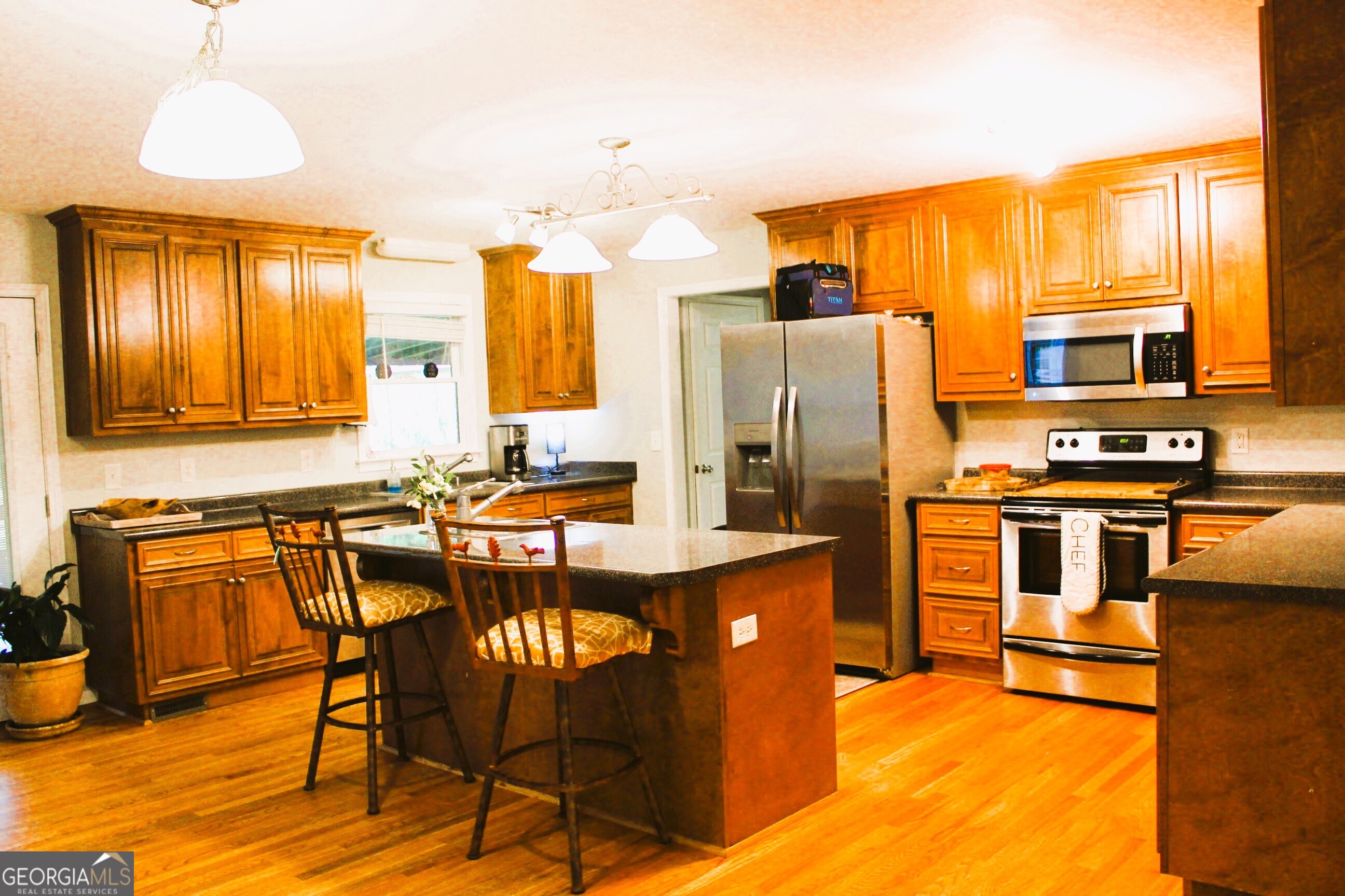 2796 Barbon Road Monroe, GA 30656 - Photo 14 of 36 a kitchen with stainless steel appliances granite countertop a refrigerator a stove a sink a dining table and chairs with wooden floor