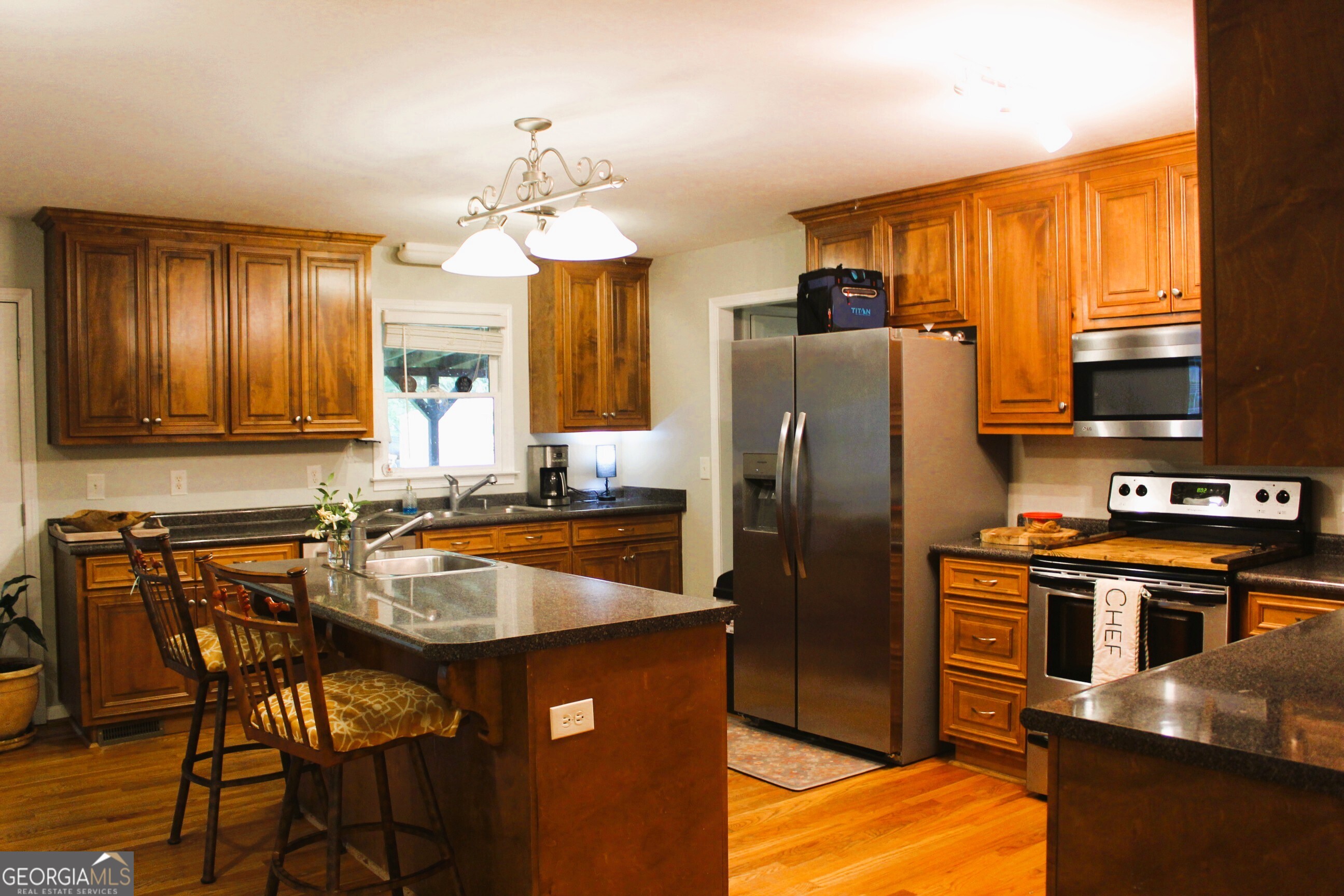 2796 Barbon Road Monroe, GA 30656 - Photo 15 of 36 a kitchen with stainless steel appliances granite countertop a refrigerator a stove a sink a dining table and chairs with wooden floor