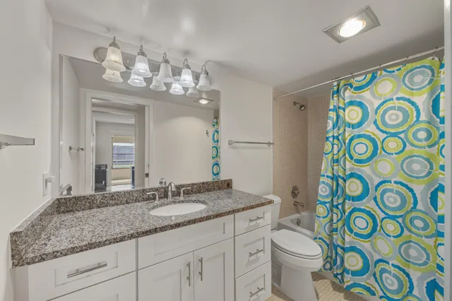 a bathroom with a granite countertop toilet a sink and a mirror