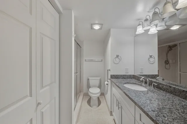 a bathroom with a granite countertop sink a toilet and a mirror