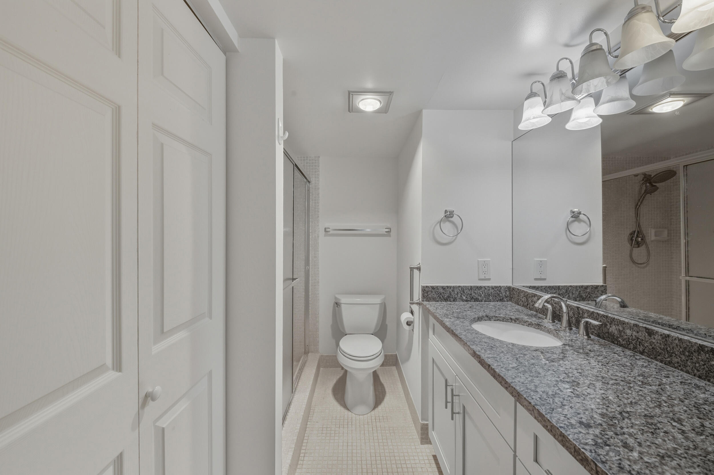 3063 Yarmouth C Boca Raton, FL 33434 - Photo 37 of 40 a bathroom with a granite countertop sink a toilet and a mirror