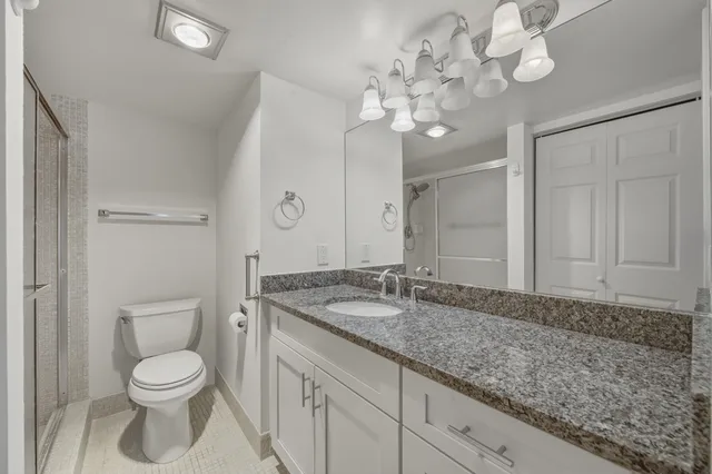 a bathroom with a granite countertop sink a toilet and a mirror