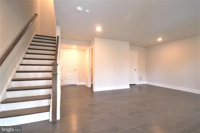 a view of an empty room with wooden floor and stairs