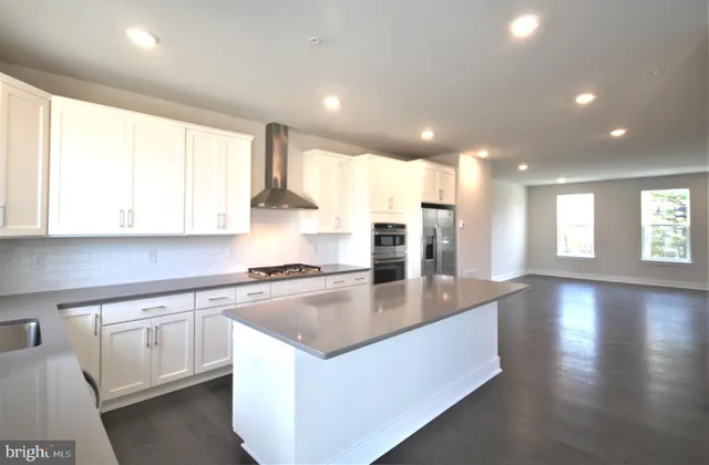 a large kitchen with stainless steel appliances granite countertop a lot of counter space and wooden floor