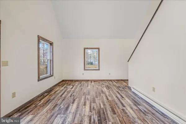 a view of an empty room with window and wooden floor