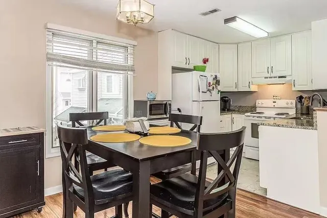 a kitchen with stainless steel appliances granite countertop a stove a refrigerator a sink dishwasher a dining table and chairs with wooden floor