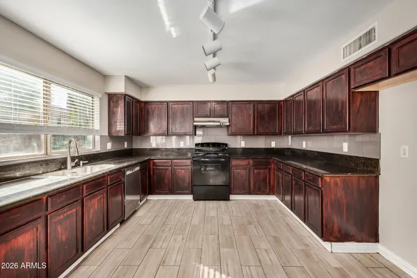 a kitchen with kitchen island granite countertop wooden cabinets stainless steel appliances a sink and a window