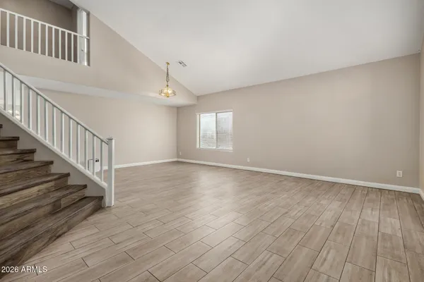 a view of an empty room with wooden floor and fan