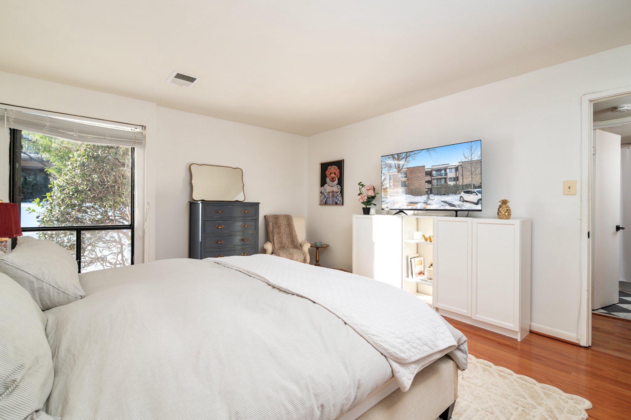 2110 Bonnywood Lane, Unit 3102 Silver Spring, MD 20902 - Photo 13 of 19 a spacious bedroom with a bed a dresser a mirror and window