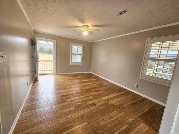 an empty room with wooden floor and windows