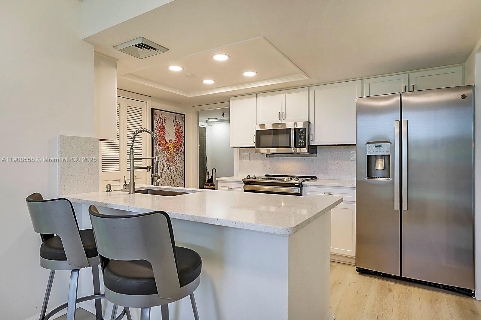 5390 Woodland Lakes Drive, Unit 301 Palm Beach Gardens, FL 33418 - Photo 17 of 34 a kitchen with kitchen island a refrigerator stove and microwave