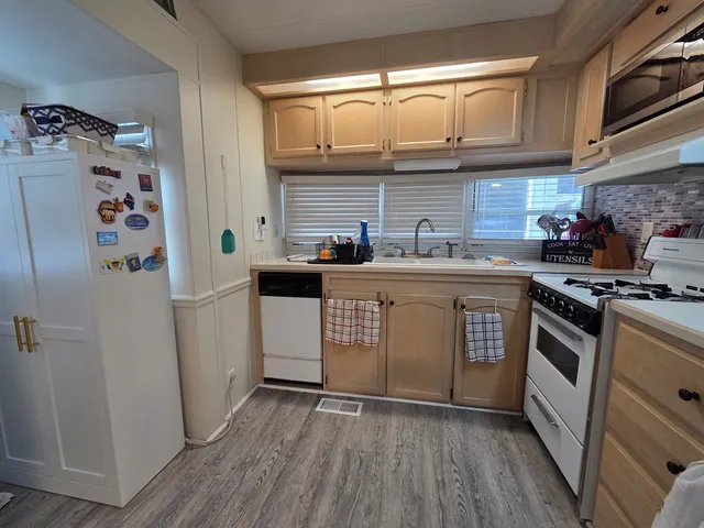 a kitchen with stainless steel appliances granite countertop a sink a stove a refrigerator and cabinets