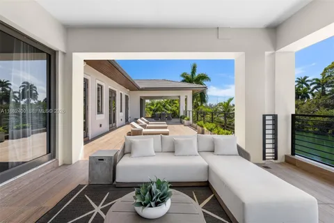 a view of a patio with couches chairs potted plants and floor to ceiling window with yard