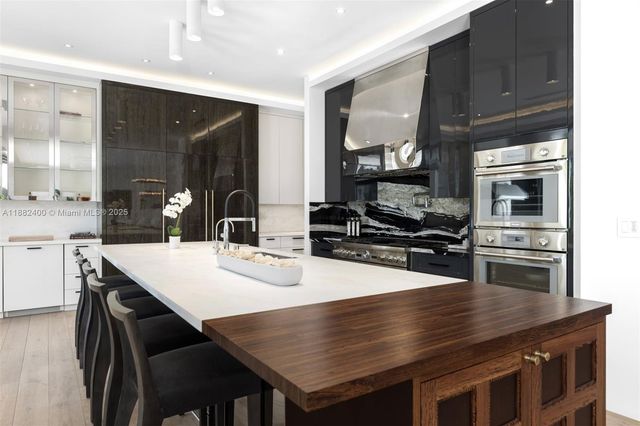 a kitchen with granite countertop a dining table chairs cabinets and stainless steel appliances