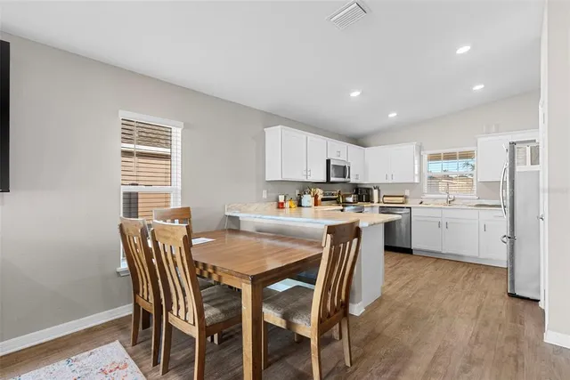 a kitchen with a table chairs refrigerator and cabinets