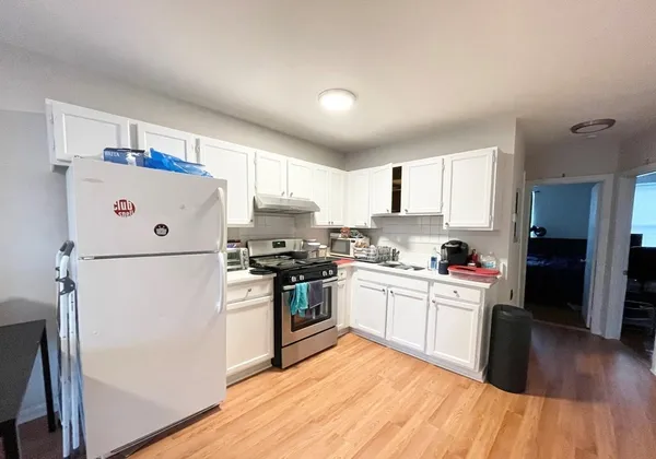 a kitchen with a refrigerator a stove top oven a sink dishwasher and white cabinets with wooden floor