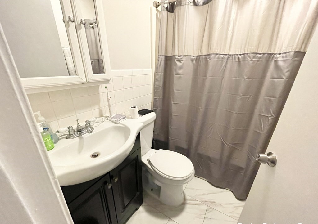 90 Hammond Street, Unit 5 Boston, MA 02120 - Photo 5 of 6 a bathroom with a sink a toilet and shower curtain
