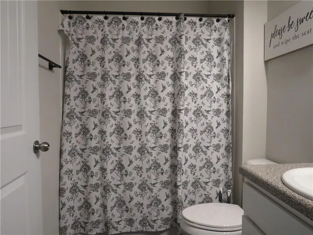a bathroom with a toilet and a shower curtain