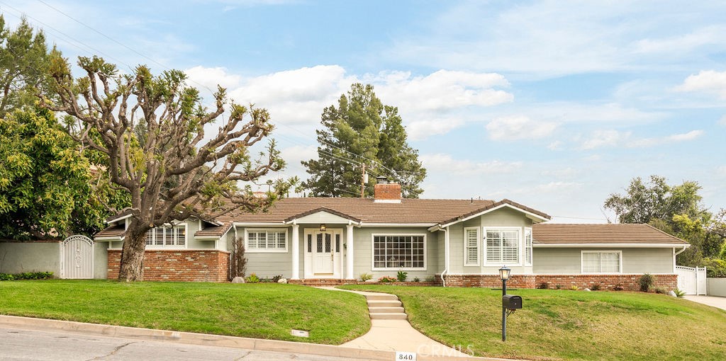 a front view of a house with a garden and trees