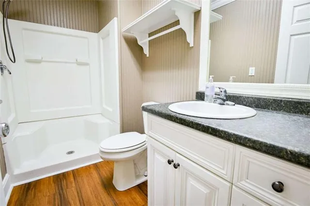 an empty room with wooden floor chandelier fan and windows