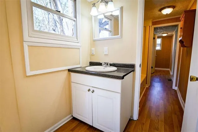 a view of a bathroom with wooden floor and a hallway