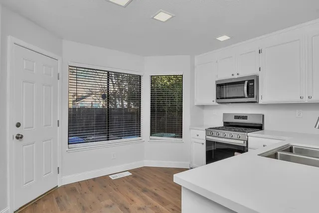 a kitchen with cabinets stainless steel appliances a sink and wooden floor