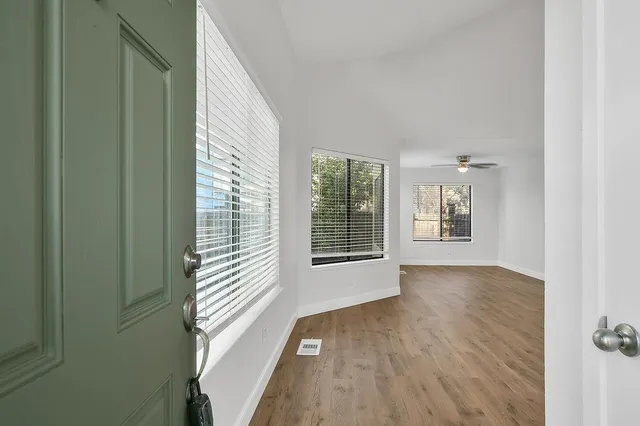 a view of an empty room with wooden floor and a window