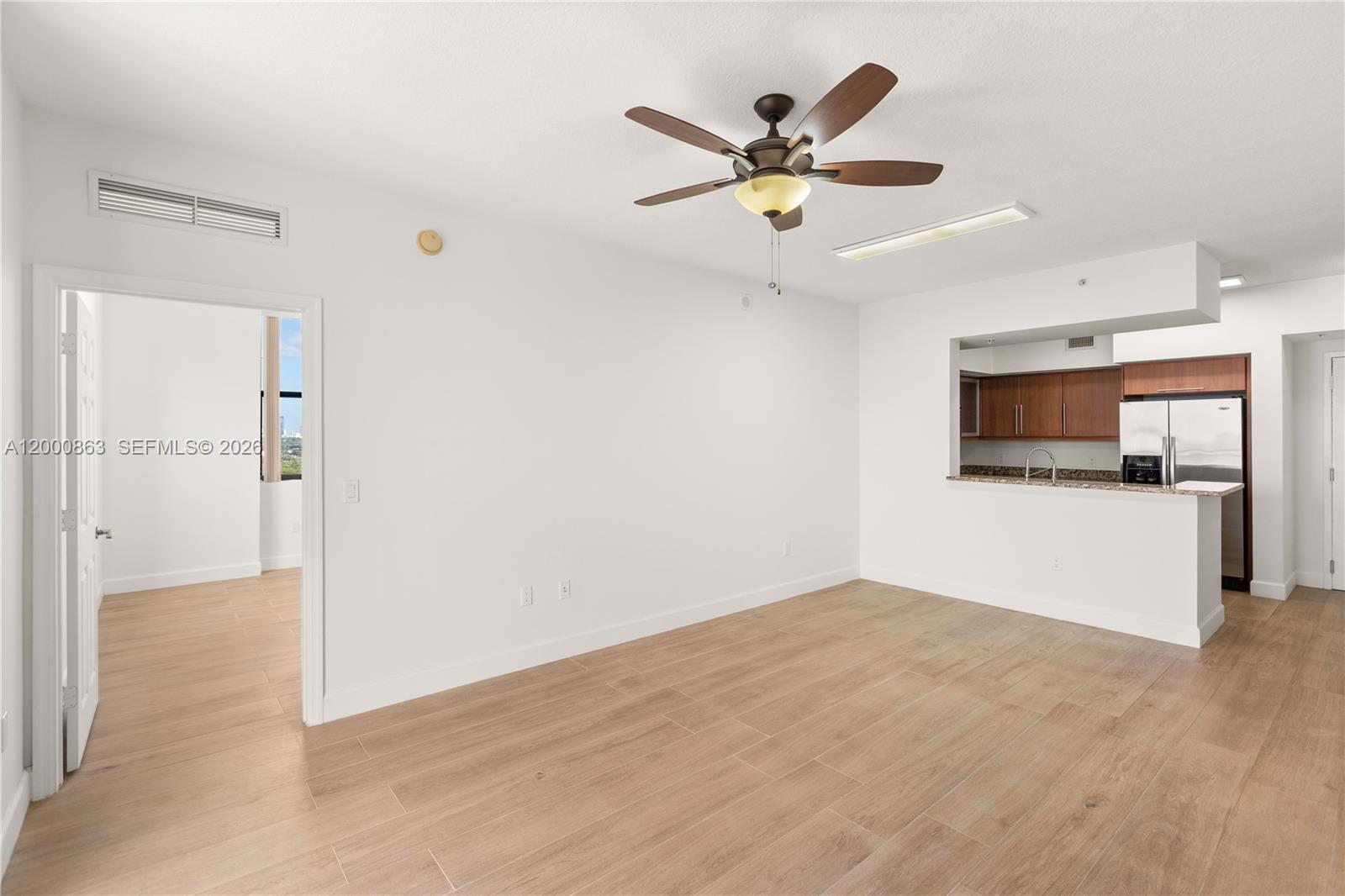 888 Douglas Road, Unit PH01 Coral Gables, FL 33134 - Photo 18 of 31 a view of a livingroom with a kitchen space with wooden floor and a ceiling fan