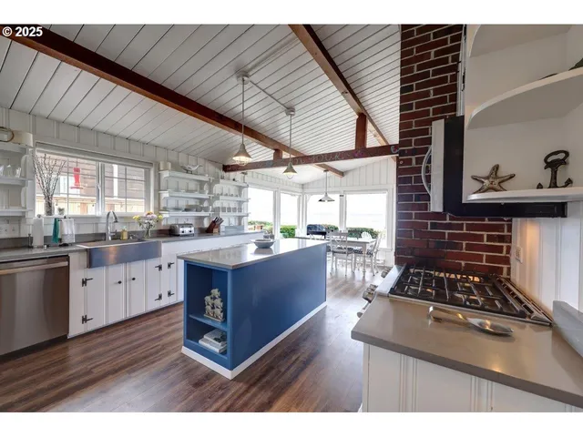 a kitchen with stainless steel appliances kitchen island granite countertop a stove a sink dishwasher and cabinets with wooden floor