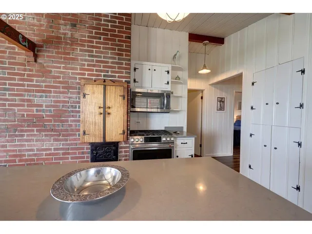 a kitchen with stainless steel appliances a stove a refrigerator a sink a chimney and a dining table