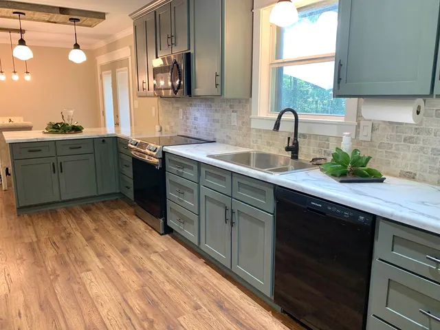 a kitchen with stainless steel appliances granite countertop a sink a stove and a wooden cabinets