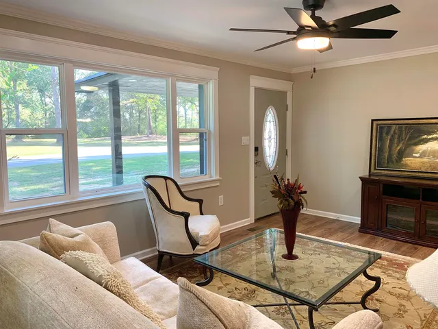 a living room with furniture a flat screen tv and a floor to ceiling window