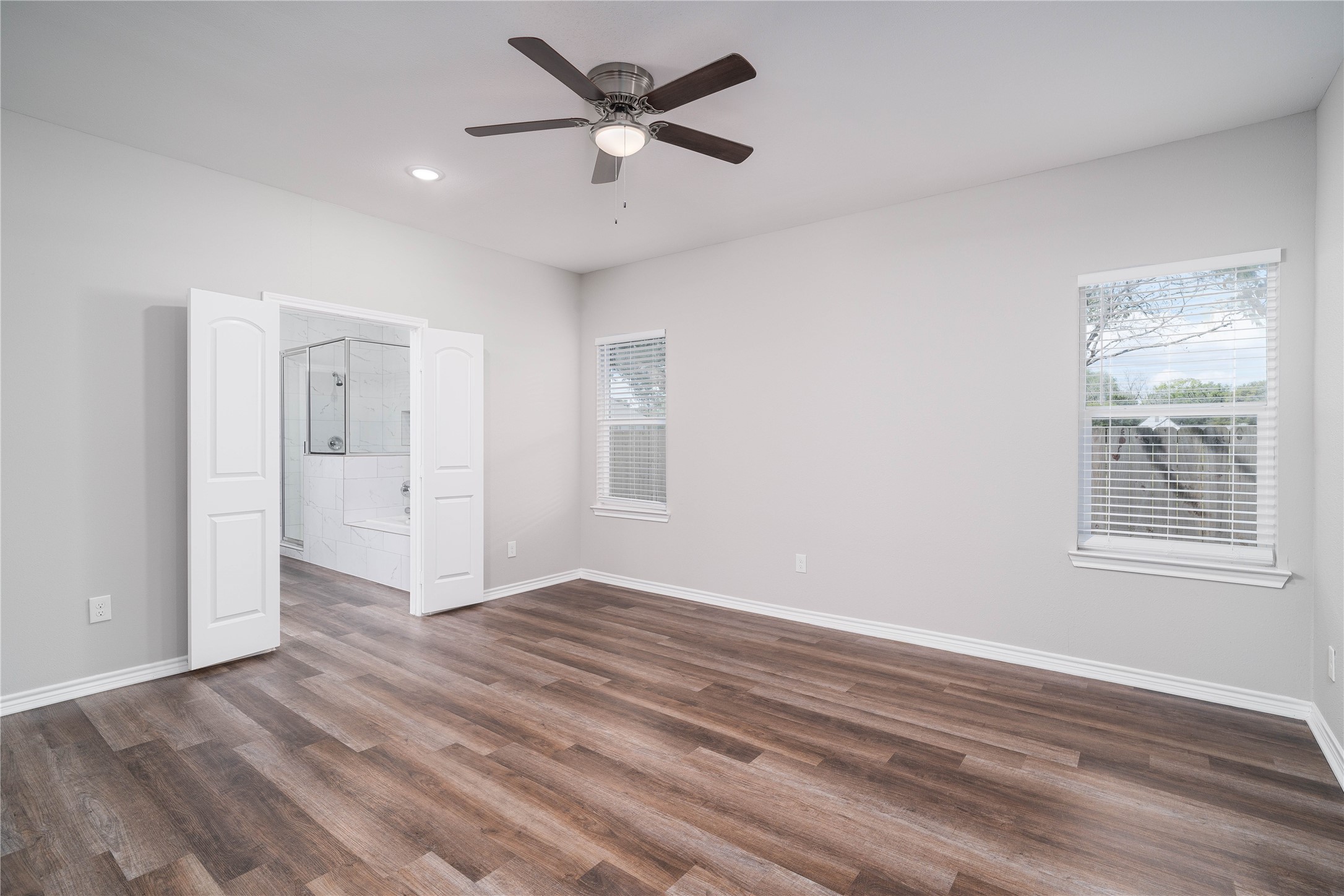 231 McCormick Street Columbus, TX 78934 - Photo 11 of 27 Primary Bedroom – Expansive primary suite featuring multiple windows, ceiling fan, and plenty of room for a full furniture set.