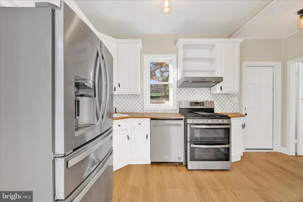 a view of a big room with wooden floor and a kitchen