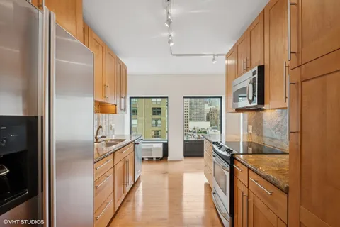 a kitchen with stainless steel appliances granite countertop a refrigerator a sink and a stove