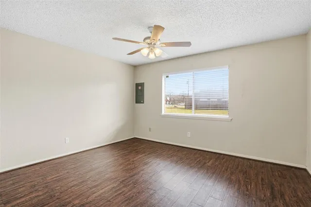 an empty room with wooden floor fan and windows