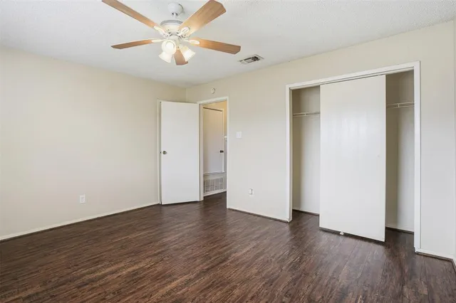 an empty room with wooden floor and a ceiling fan