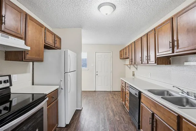 a kitchen with stainless steel appliances granite countertop a refrigerator a sink dishwasher a stove and a microwave oven on granite countertops