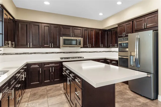 a kitchen with kitchen island a counter top space cabinets and stainless steel appliances