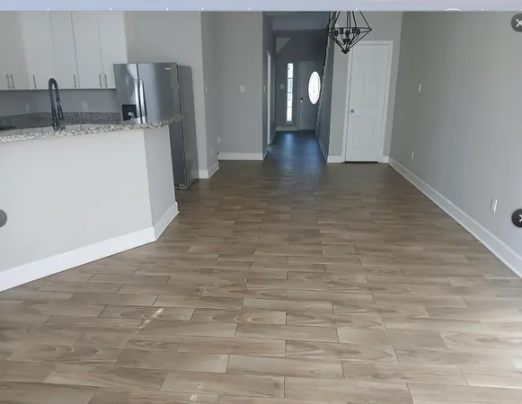 a view of a refrigerator in kitchen and an empty room