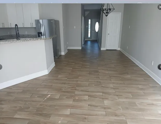 a view of a refrigerator in kitchen and an empty room
