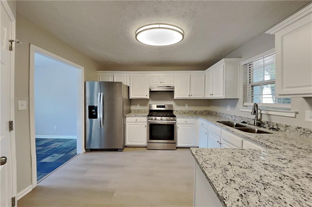3366 English Oaks Drive Northwest Kennesaw, GA 30144 - Photo 4 of 22 a kitchen with stainless steel appliances granite countertop a stove a sink and a refrigerator