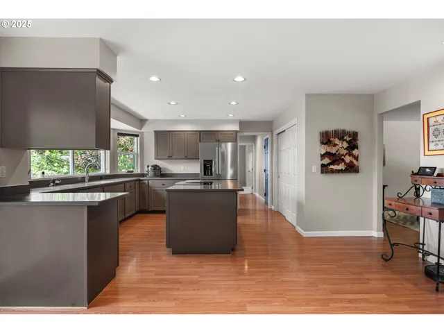 a living room with stainless steel appliances granite countertop furniture wooden floor and a window